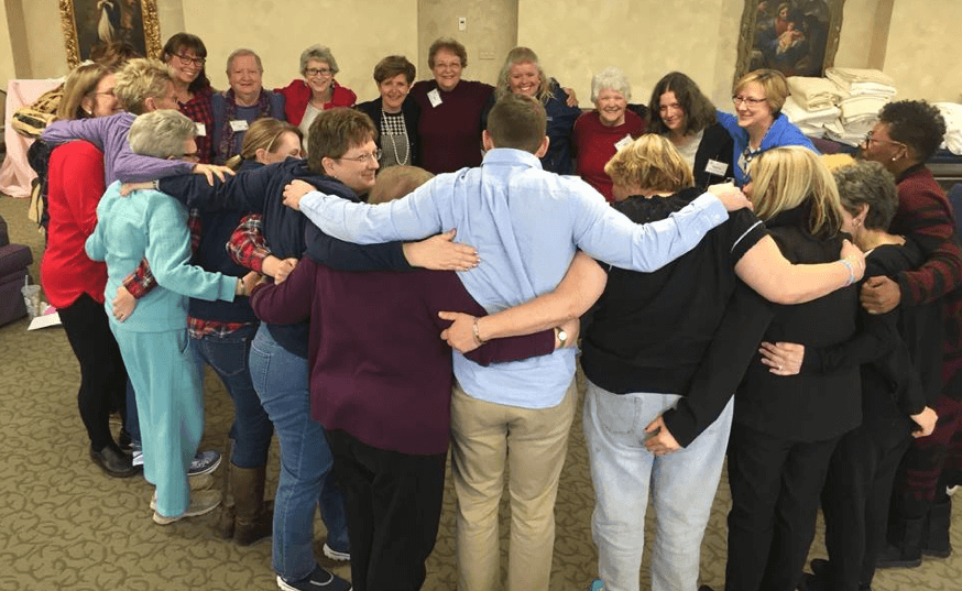 People join in a group hug during a metastatic breast cancer retreat.