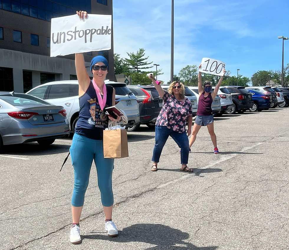 Natalie with an unstoppable sign in a parking lot with two girl friends