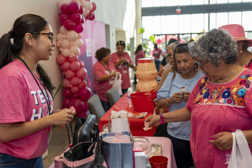 Latina women interacting at a breast cancer health fair