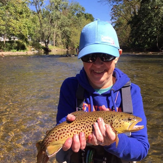 Barbara in a river holding a fish