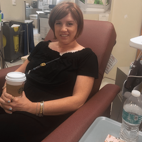 Emily sitting on a chemo chair getting her chemo with a coffee on her hands