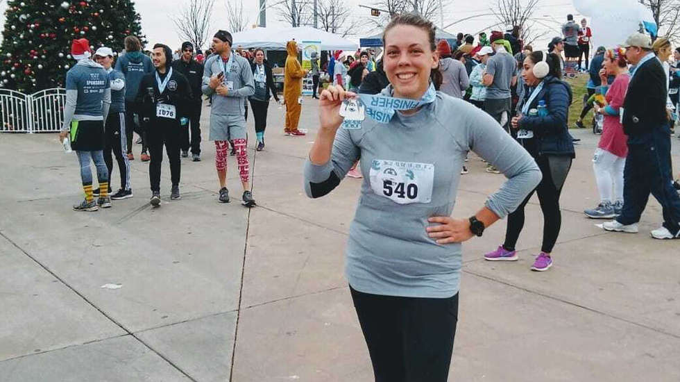 Rebekah holding a marathon finisher medal 