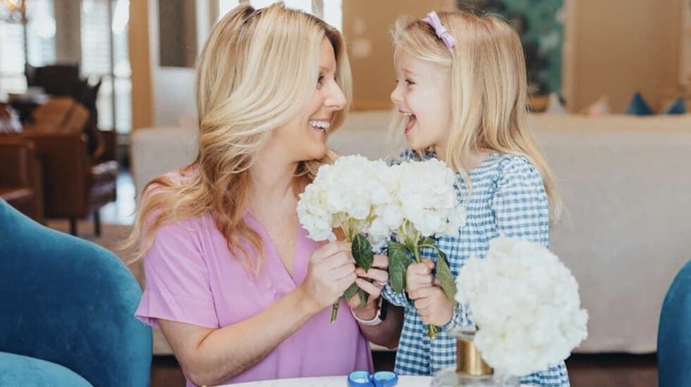 Jennifer and her daughter Harper smiling over flowers