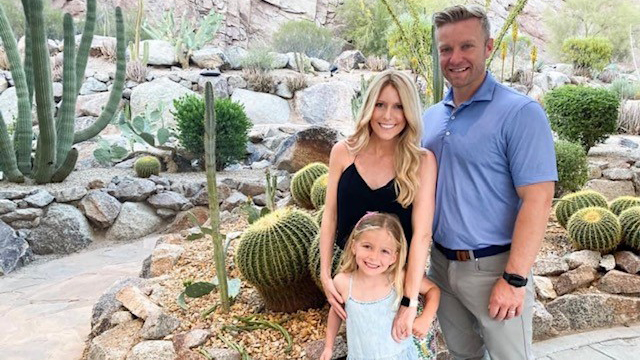 Jennifer with her husband and daughter Harper outdoors in front of cacti garden